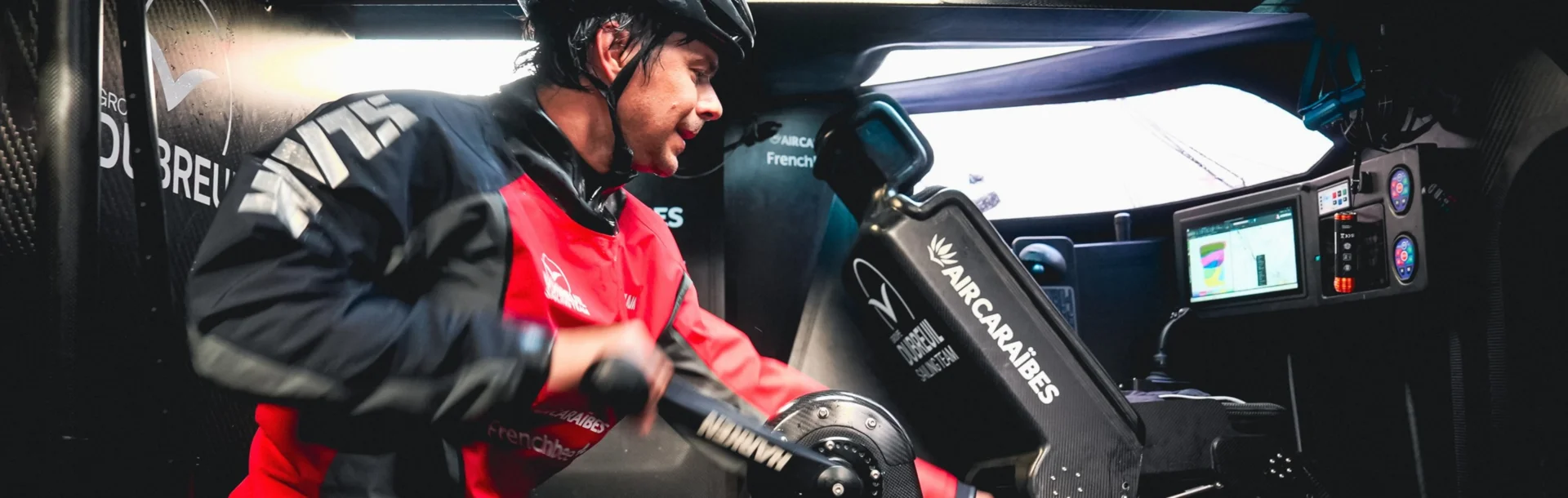 Sébastien Simon actionne le moulin de winch dans le cockpit fermé de l'IMOCA Groupe Dubreuil 2.