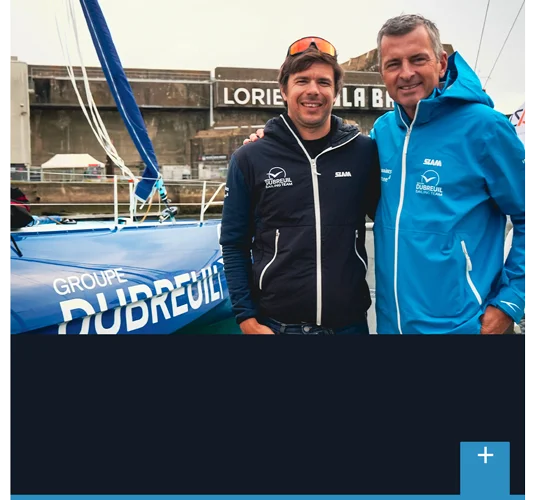 Découvrir le partenariat voile : Sébastien Simon et Paul-Henri Dubreuil devant le bateau Groupe Dubreuil 2 à Lorient.